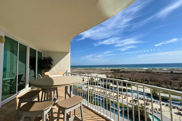 balcony with a water view and a view of the beach