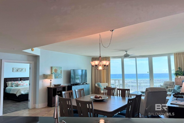 dining space with ceiling fan with notable chandelier, a wall of windows, and light tile patterned flooring