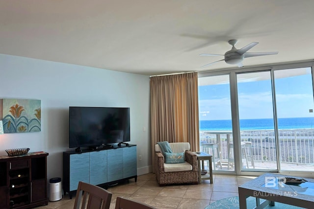 living area with light tile patterned floors, ceiling fan, baseboards, and a wall of windows