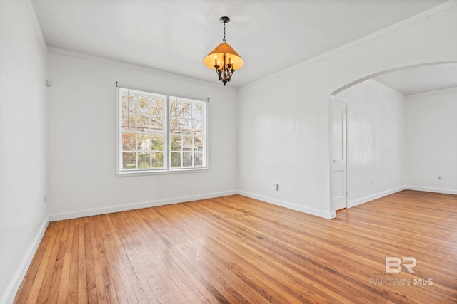 spare room with baseboards, arched walkways, crown molding, light wood-type flooring, and a chandelier