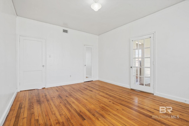 empty room featuring visible vents, crown molding, baseboards, and hardwood / wood-style flooring