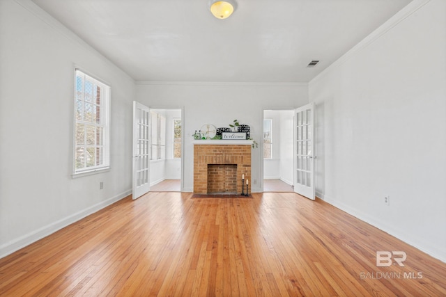 unfurnished living room featuring french doors, a brick fireplace, and light wood finished floors