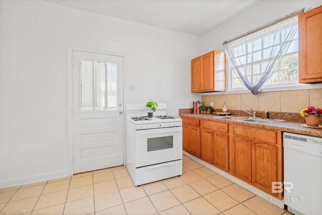 kitchen with decorative backsplash, white appliances, light tile patterned floors, and a sink