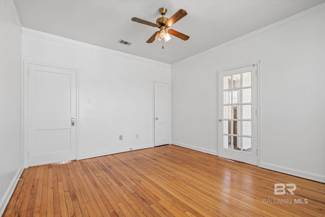 empty room featuring crown molding, a ceiling fan, visible vents, and light wood finished floors