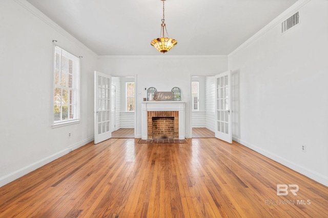 unfurnished living room with hardwood / wood-style floors, baseboards, visible vents, and a fireplace