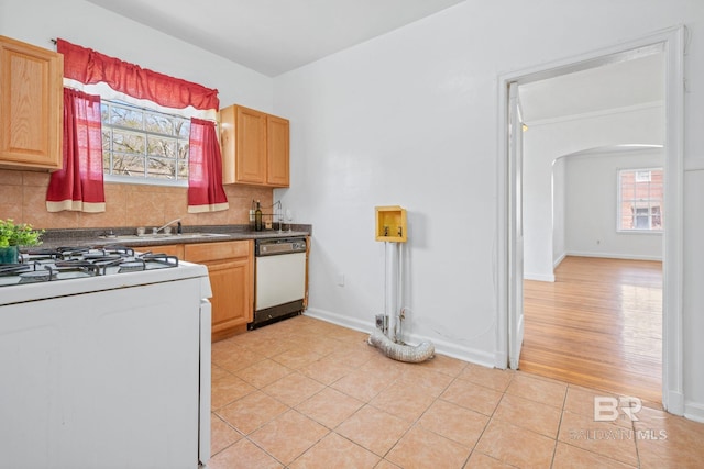 kitchen featuring a sink, backsplash, white appliances, arched walkways, and light tile patterned floors