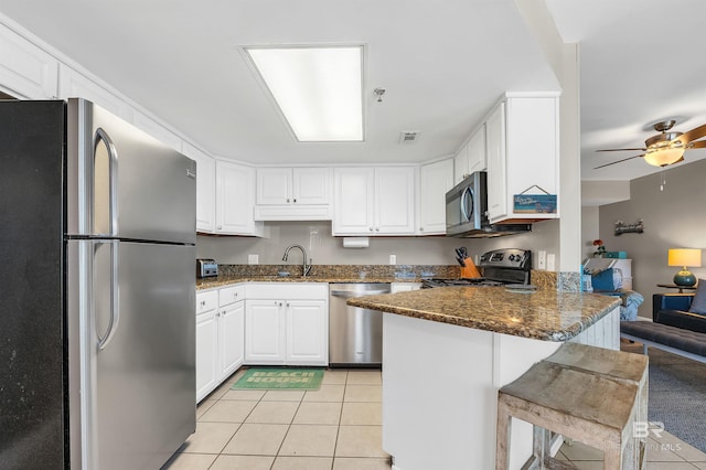24230 Perdido Beach Blvd Unit 3077, Orange Beach, AL 36561 - kitchen with light tile patterned floors, a peninsula, white cabinetry, dark stone countertops, and appliances with stainless steel finishes