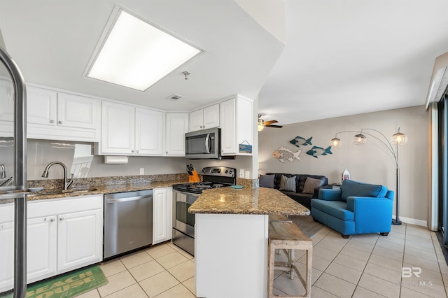24230 Perdido Beach Blvd Unit 3077, Orange Beach, AL 36561 - kitchen with white cabinets, a sink, open floor plan, appliances with stainless steel finishes, and a peninsula