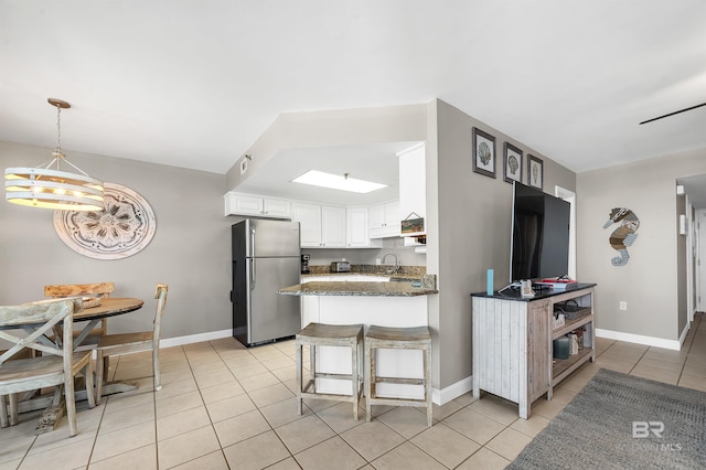24230 Perdido Beach Blvd Unit 3077, Orange Beach, AL 36561 - kitchen featuring light tile patterned floors, freestanding refrigerator, a peninsula, white cabinetry, and dark stone counters