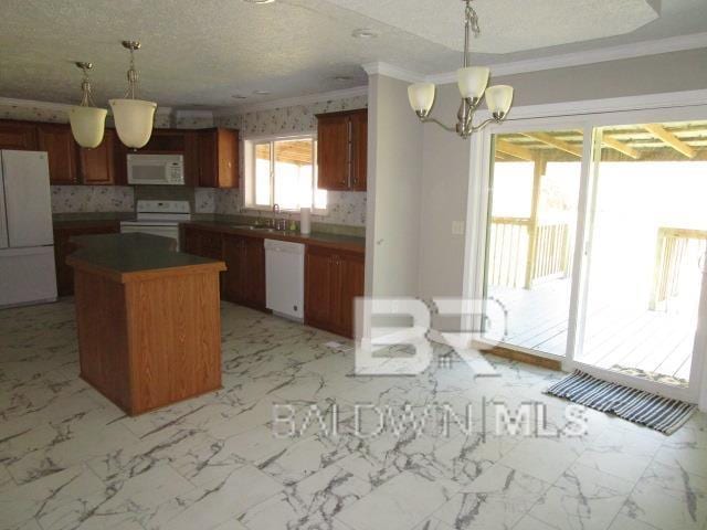 kitchen with dark countertops, hanging light fixtures, a kitchen island, a sink, and white appliances