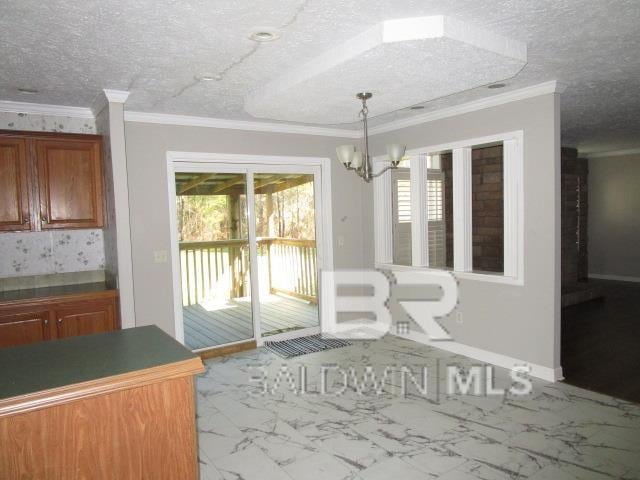 unfurnished dining area featuring a textured ceiling, marble finish floor, ornamental molding, and a wealth of natural light