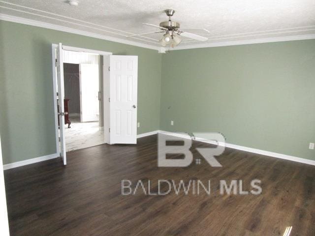 unfurnished room featuring ceiling fan, ornamental molding, dark wood-style flooring, and baseboards