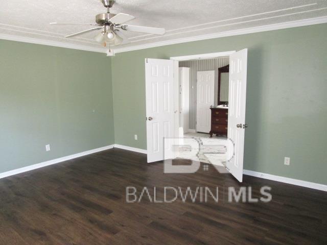 unfurnished room with ornamental molding, dark wood-style flooring, and baseboards