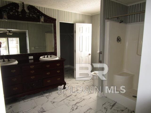 full bathroom with marble finish floor, vanity, a shower stall, a textured ceiling, and wallpapered walls