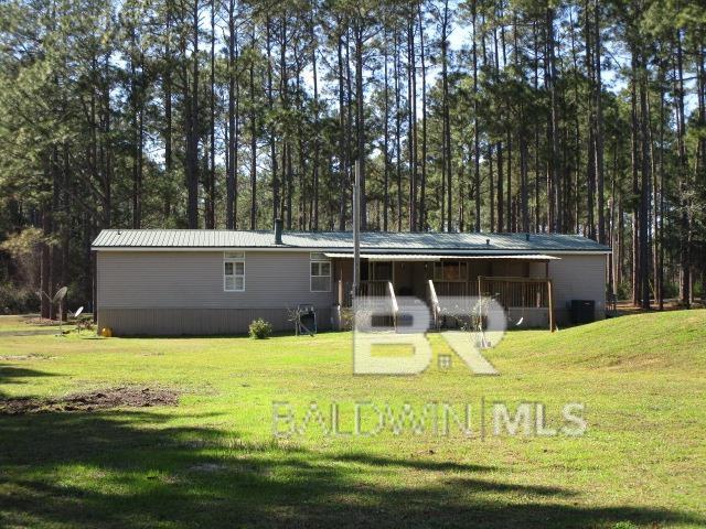 back of house featuring covered porch, metal roof, and a yard