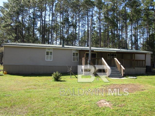 rear view of house with metal roof and a yard