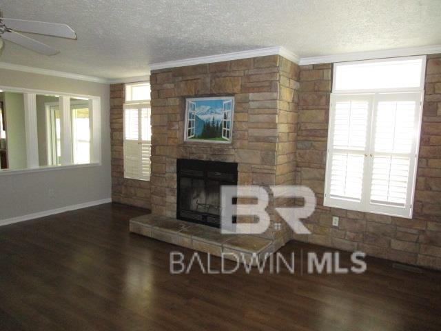 living area with dark wood-style floors, a fireplace, crown molding, and a textured ceiling