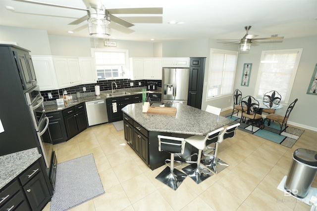 kitchen featuring a kitchen island, light stone countertops, white cabinetry, and appliances with stainless steel finishes