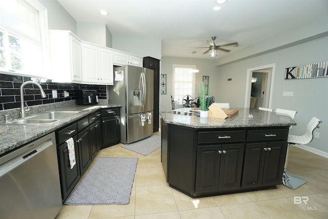 kitchen with appliances with stainless steel finishes, white cabinetry, a kitchen island, and sink