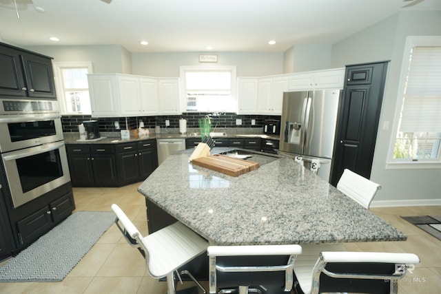 kitchen featuring white cabinets, a large island, a breakfast bar area, and appliances with stainless steel finishes