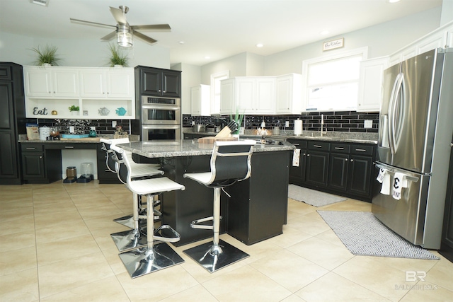 kitchen with a kitchen island, light stone countertops, white cabinetry, and appliances with stainless steel finishes