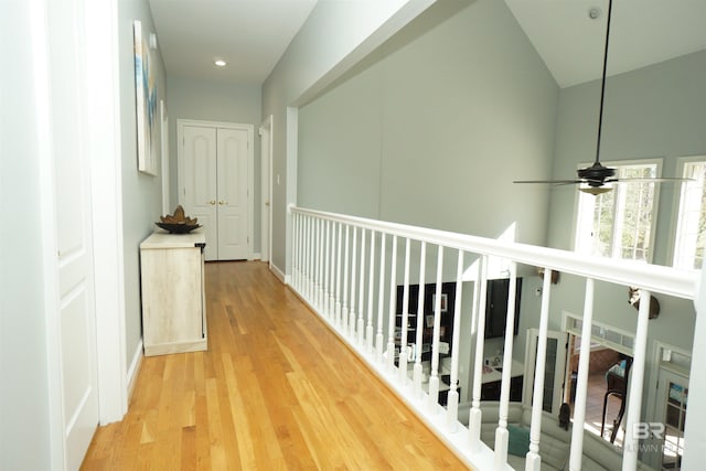 hall featuring light wood-type flooring and high vaulted ceiling