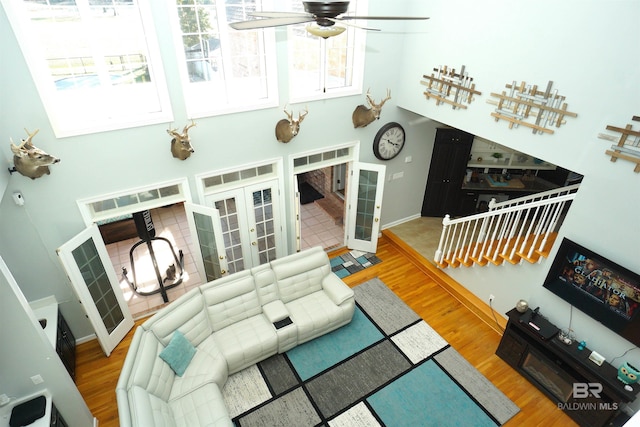 living room with french doors, hardwood / wood-style flooring, ceiling fan, and a high ceiling