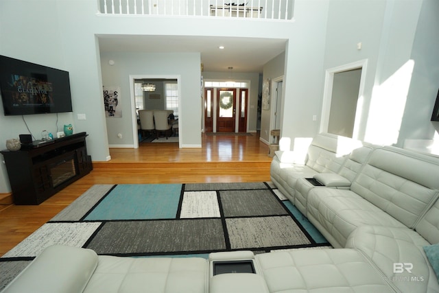 living room with wood-type flooring and a towering ceiling