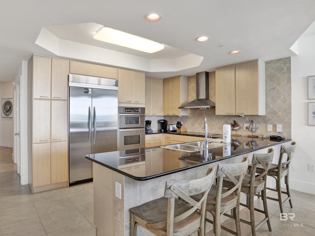 28105 Perdido Beach Blvd Unit C504, Orange Beach, AL 36561 - kitchen featuring a raised ceiling, light brown cabinetry, wall chimney exhaust hood, and appliances with stainless steel finishes
