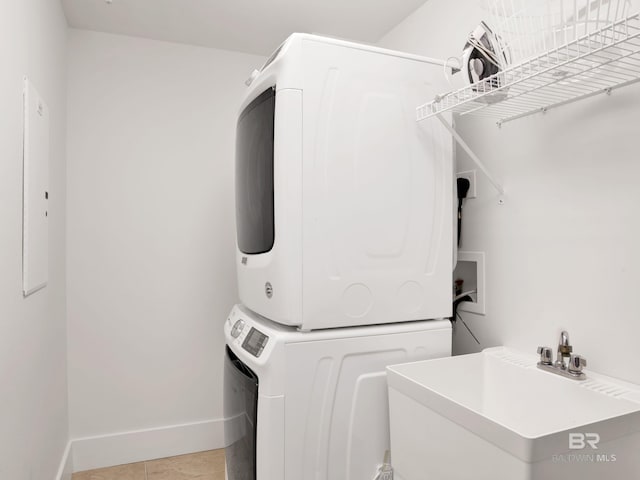 28105 Perdido Beach Blvd Unit C504, Orange Beach, AL 36561 - clothes washing area with a sink, light tile patterned flooring, baseboards, stacked washer and clothes dryer, and laundry area