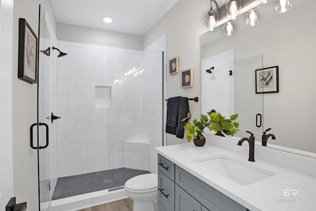 bathroom featuring toilet, vanity, and a stall shower