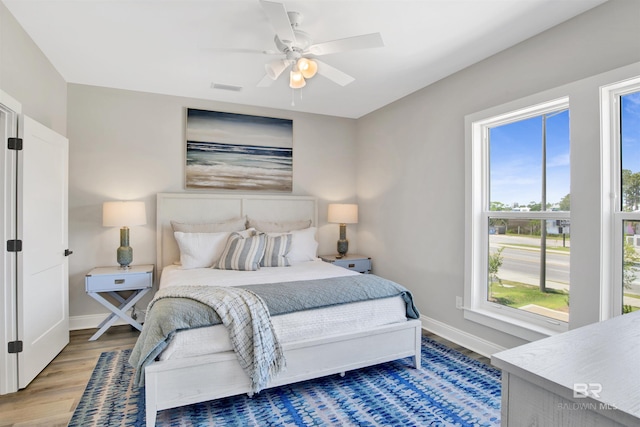 bedroom featuring wood finished floors, baseboards, ceiling fan, and visible vents