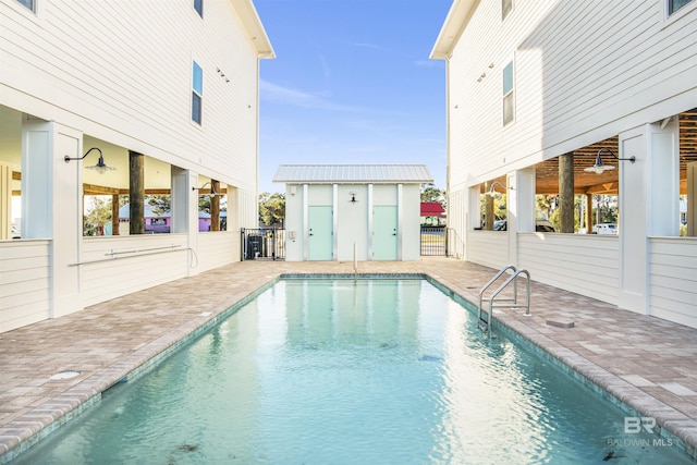 pool featuring an outdoor structure, fence, and a patio area
