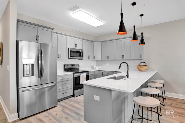 kitchen with hanging light fixtures, backsplash, kitchen peninsula, stainless steel appliances, and a kitchen bar