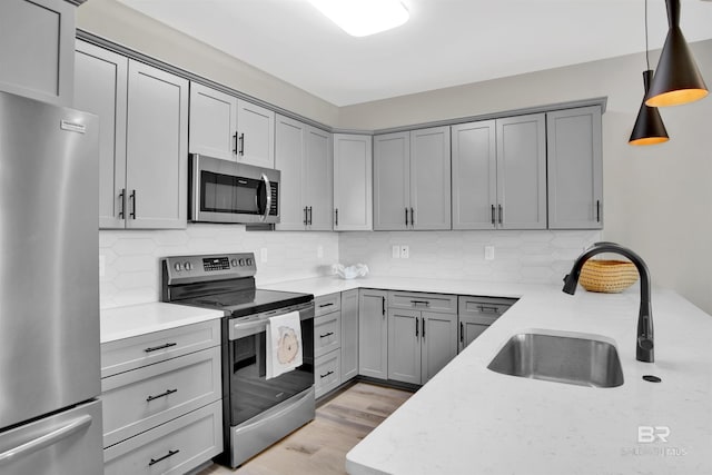 kitchen featuring a sink, gray cabinetry, appliances with stainless steel finishes, and tasteful backsplash