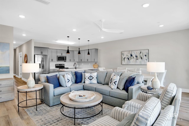 living room featuring light wood finished floors, baseboards, recessed lighting, and a ceiling fan