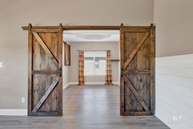 foyer entrance with hardwood / wood-style floors, a barn door, and wood walls