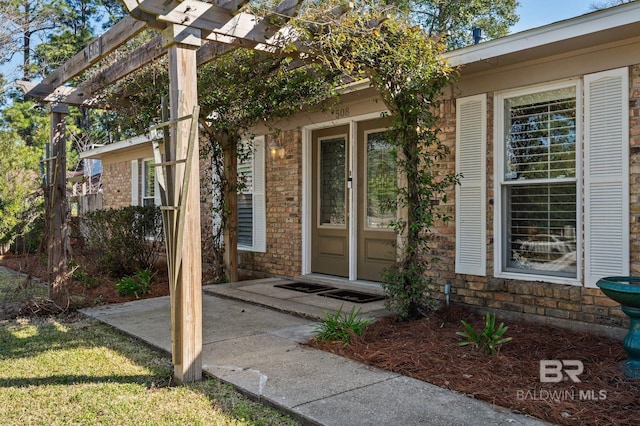 view of exterior entry featuring a patio and a pergola