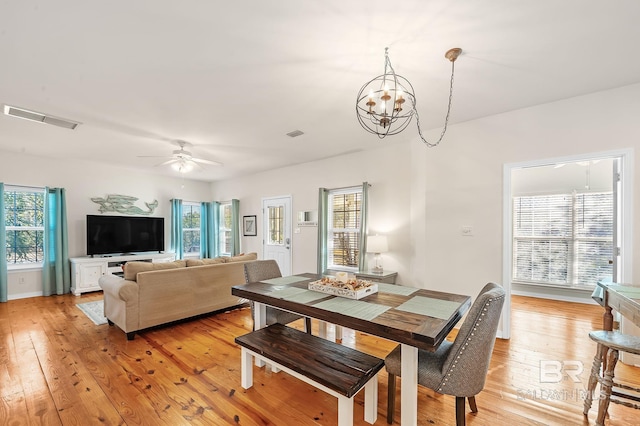 dining space featuring ceiling fan with notable chandelier, a wealth of natural light, and light hardwood / wood-style floors