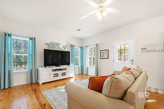 living room with ceiling fan, light wood-type flooring, and a wealth of natural light