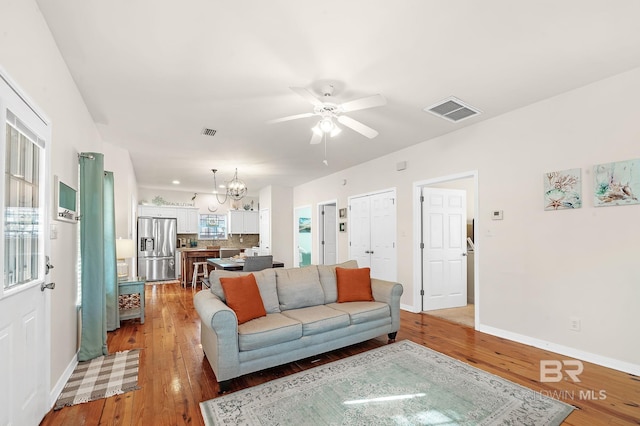 living room with hardwood / wood-style floors and ceiling fan with notable chandelier