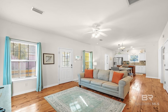 living room featuring sink, ceiling fan with notable chandelier, and light hardwood / wood-style floors