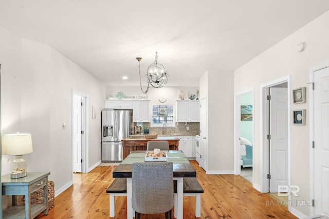 dining area featuring an inviting chandelier, sink, and light wood-type flooring