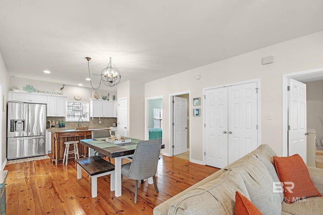 dining space featuring sink, light hardwood / wood-style floors, and a chandelier