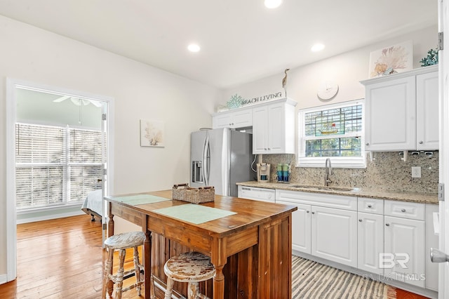 kitchen with stainless steel refrigerator with ice dispenser, sink, tasteful backsplash, and white cabinets