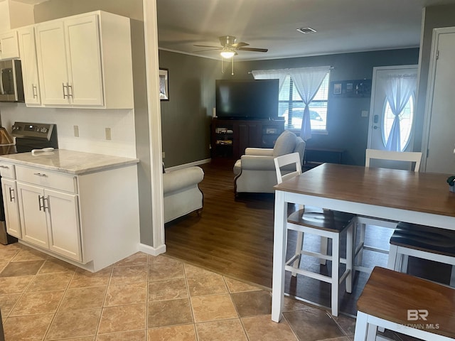 2274 Foshee Rd, Brewton, AL 36426 - kitchen featuring appliances with stainless steel finishes, ceiling fan, white cabinetry, open floor plan, and light stone counters