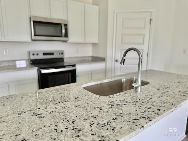 kitchen featuring range with electric cooktop, sink, white cabinets, and light stone counters