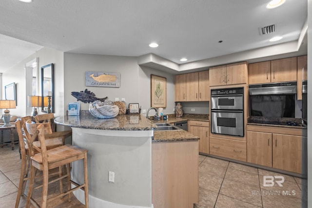 521 W Beach Blvd Unit 1702, Gulf Shores, AL 36542 - kitchen with double oven, a peninsula, light tile patterned floors, a breakfast bar area, and dark stone counters