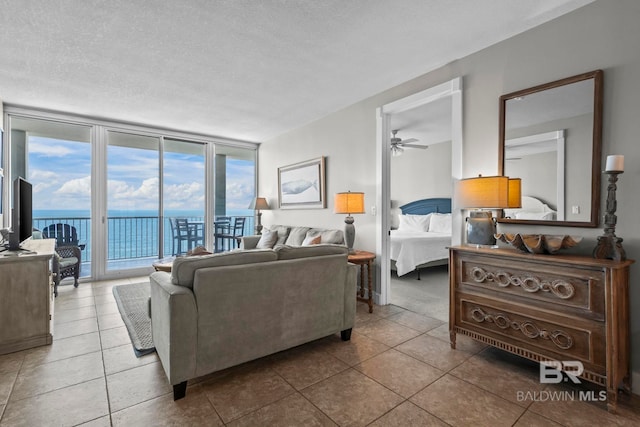 521 W Beach Blvd Unit 1702, Gulf Shores, AL 36542 - tiled living area with ceiling fan, expansive windows, a water view, and a textured ceiling