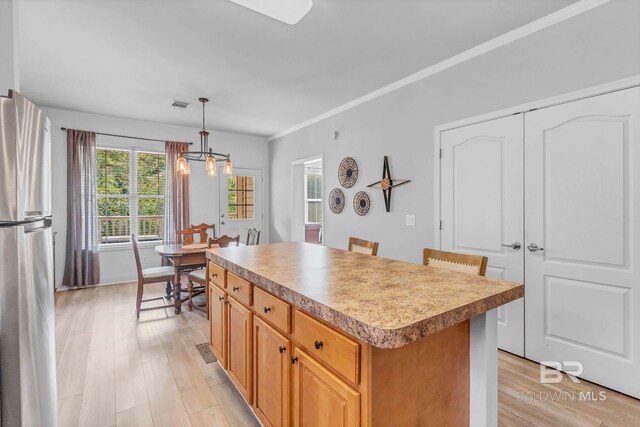 25806 Pollard Rd Unit 204, Daphne, AL 36526 - kitchen with a center island, light wood finished floors, a chandelier, freestanding refrigerator, and decorative light fixtures